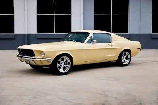 Cream 1968 Revology Mustang GT Fastback parked in a front three-quarter view.