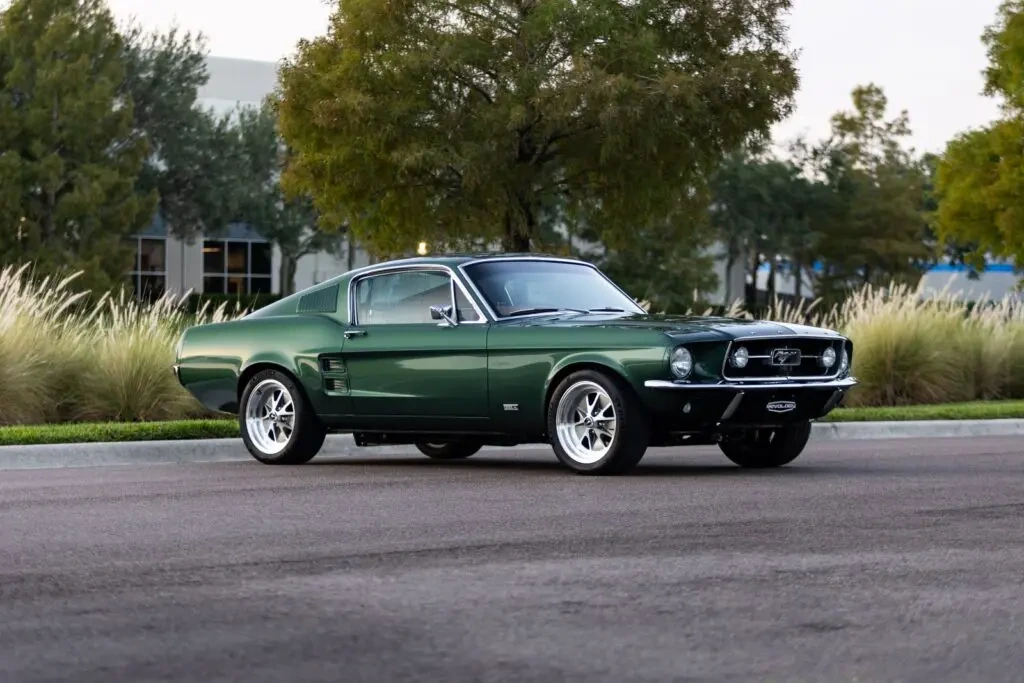 Dark green 1967 Ford Mustang fastback parked on a quiet street with landscaped background